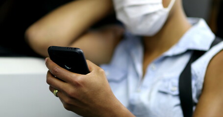 Commuter african woman wearing face mask checking cellphone while riding subway