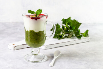 Delicious dessert with a layer of yogurt, nettle smoothie and honeysuckle jam. Dessert is served in a glass with a spoon. Copy space