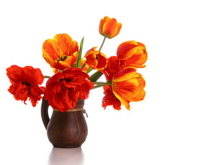 Bouquet of bright tulips in a clay jug isolated on a white background. Copy space