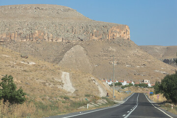 Desert highway and ancient dwellings in caves in the rocks at sunset on Kayseri province, Turkey,...