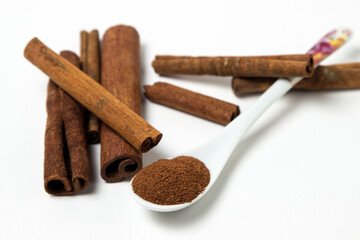 Cinnamon on a white background. Spoon ground cinnamon next to whole cinnamon. delicious spice