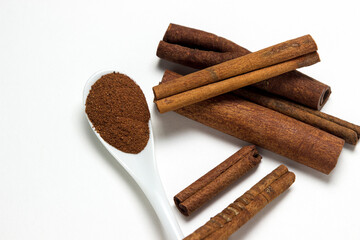 Cinnamon on a white background. Spoon ground cinnamon next to whole cinnamon. delicious spice