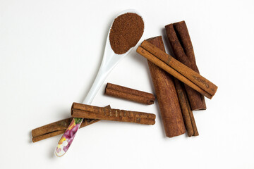 Cinnamon on a white background. Spoon ground cinnamon next to whole cinnamon. delicious spice