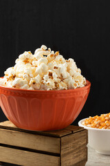 Salty popcorn in a orange bowl.