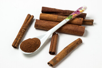 Cinnamon on a white background. Spoon ground cinnamon next to whole cinnamon. delicious spice