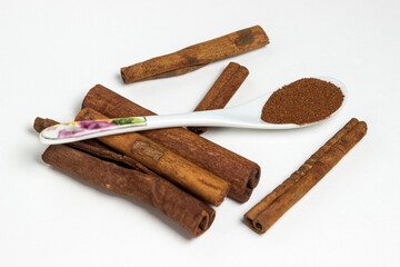 Cinnamon on a white background. Spoon ground cinnamon next to whole cinnamon. delicious spice
