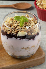 Focus on a glass cup of strawberry yogurt with granola and chia.