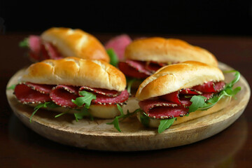 Selective focus. Macro. Salami sandwiches with arugula and mustard on a wooden board.