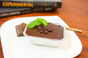 Chocolate cake decorated with chocolate sauce on a wooden table.