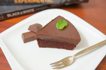 Chocolate cake decorated with chocolate sauce on a wooden table.