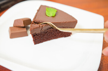 Chocolate cake decorated with chocolate sauce on a wooden table.