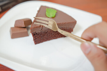 Chocolate cake decorated with chocolate sauce on a wooden table.
