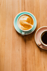 Two cups of aromatic coffee on a wooden table view from above. Aromatic cappuccino with beautiful foam and black coffee Americano flatlay