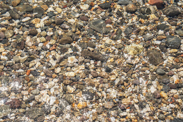Pebbles under water. Sea stones in the sea water. The view from the top. Nautical background. Transparent sea.