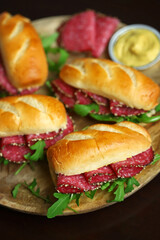 Selective focus. Macro. Salami sandwiches with arugula and mustard on a wooden board.