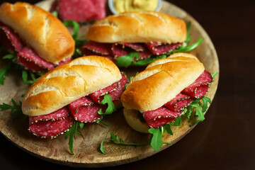 Selective focus. Macro. Salami sandwiches with arugula and mustard on a wooden board.