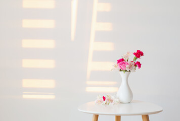 flowers in  white vase on white background in sunlight