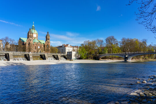 Isar river in Munich with saint Lukas dome cathedral and bridge