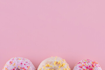 pink and yellow sprinkled  donuts on a pink background Space for text