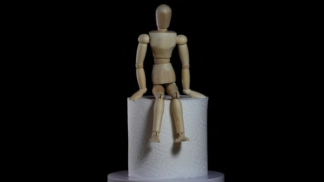 footage of toilet paper wooden figure dark background