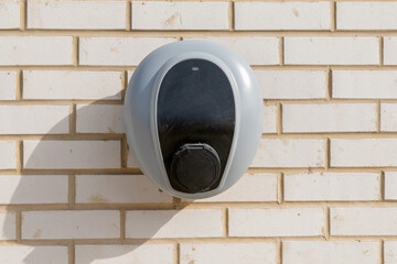 Private electric vehicle charging station fitted to the face of a white brick wall