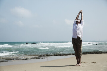 Fototapeta na wymiar Yoga lesson. A man practices yoga near the sea.