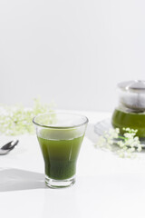 Un vaso de té verde matcha sobre una mesa blanca	