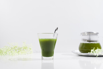 Un vaso de té verde matcha sobre una mesa blanca	