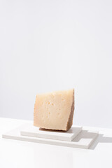 Trozo de queso manchego de oveja curado sobre una mesa blanca. Aperitivo español	
