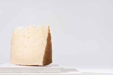 Trozo de queso manchego de oveja curado sobre una mesa blanca. Aperitivo español	
