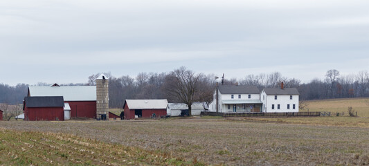 Fototapeta na wymiar Amish Farm and Homestead and an Unplowed Cornfield with Woods in the background in Early Winter | Holmes County, Ohio