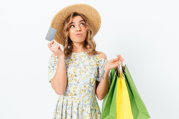 Pensive young woman holding bank card and shopping bags