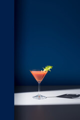 Coctel Bloody Mary decorado con hoja de apio sobre fondo azul	