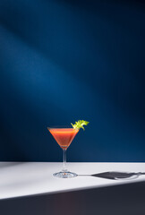 Coctel Bloody Mary decorado con hoja de apio sobre fondo azul	