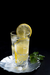 Un vaso de refrescante zumo de limón, cóctel de frutas con rodajas de limón y hielo sobre fondo negro	