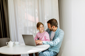 Father and daughter using laptop computer together
