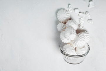 on a flat surface, a French meringue dessert is poured into a glass bowl. imitation of levitation. Meringue is made from a mixture of beaten egg whites with sugar. copy space.