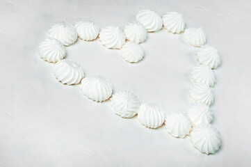 from meringue cakes - a French dessert, a heart shape with an empty middle on a gray background is laid out. Meringue is made from a mixture of beaten egg whites with sugar.