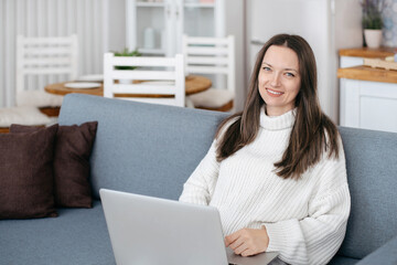 young woman with laptop sitting on the couch.