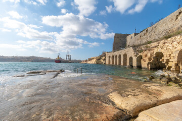 A slippery stone shore next to the harbor right next to Fort Ricasoli in the capital city of Malta, Valletta.