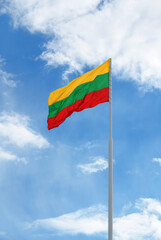 Flag of Lithuania is waving in front of blue sky and clouds