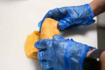 Close-Up of a person wearing disposable protective gloves making a wrap  in a kitchen