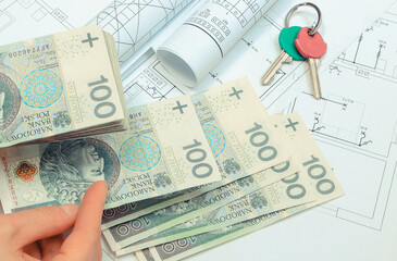 Hand of woman with money and home keys on electrical construction drawing of house. Payment for work concept