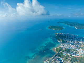 flying over group of the large green island and little city in the never ending blue ocean with cloudy and clear sky weather