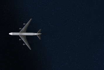 Toy airliner on a silvery dark blue background. Concept of a romantic night flight among the stars in the light of the moon. The concept of travel and relocation. Copy space.