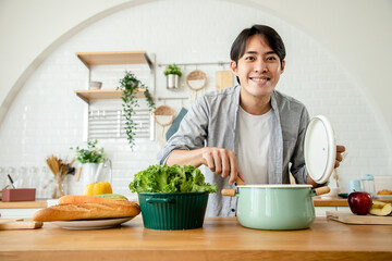 Handsome Asian man prepares breakfast after all the ingredients are cooked in the kitchen. Health care concept and eating healthy food. Good skin and good health