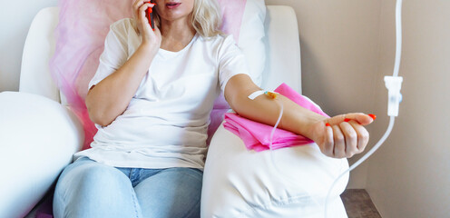 Woman in hospital talking at mobile phone while needle is in arm, Vitamin Therapy Iv Drip Infusion...