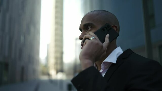 Serious African businessman talking by phone on the street