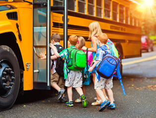 A group of young unidentifiable children getting on the schoolbus - 502799752