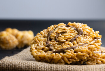 Front view closeup photo of a Thai rice cracker with sugar syrup on top put on sackcloth black background.